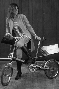 monochrome photo of 60s style fashionable woman on moulton bicycle